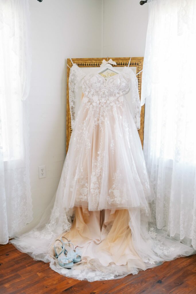 Jacob & Angelina's Holland Farms Wedding 3 Angelina's lace wedding gown hanging in a sheer-curtained window before her Holland Farms wedding in Milton, FL