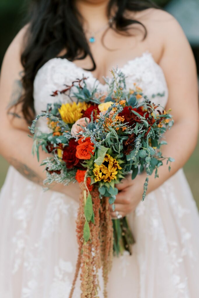 Jacob & Angelina's Holland Farms Wedding 4 Angelina holding a red, orange and yellow wedding bouquet with trailing amaranth at her Holland Farms wedding