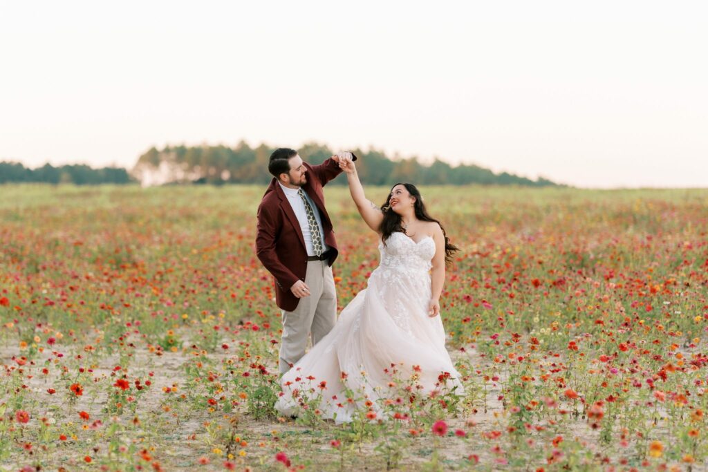Jacob & Angelina's Holland Farms Wedding 9 Jacob twirling Angelina in a field of red and orange flowers at Holland Farms in Milton, FL