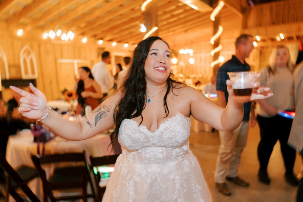Jacob & Angelina's Holland Farms Wedding 16 Angelina in her wedding dress holding a drink and laughing on the dance floor at Holland Farms