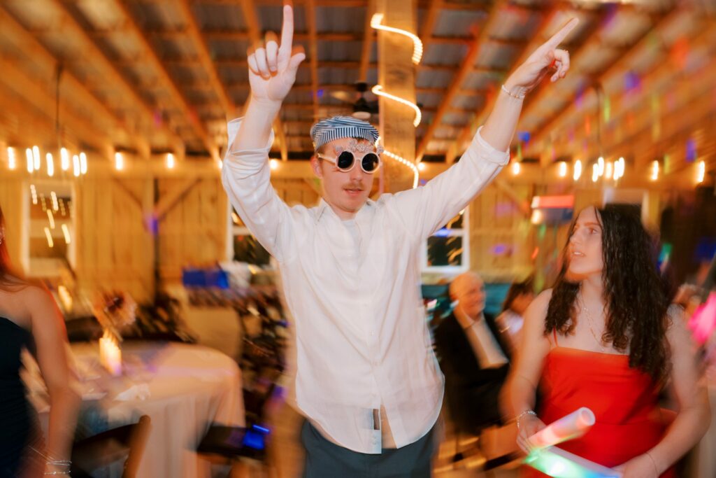 Jacob & Angelina's Holland Farms Wedding 17 Wedding guest in sunglasses with both arms raised on the dance floor at Jacob and Angelina's Holland Farms wedding