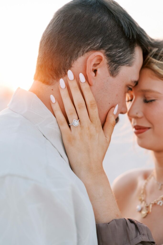 Avery & Hannah's Orange Beach Proposal 3 Hannah rests her ringed hand on Avery's face as they touch foreheads at sunset on Orange Beach, Alabama