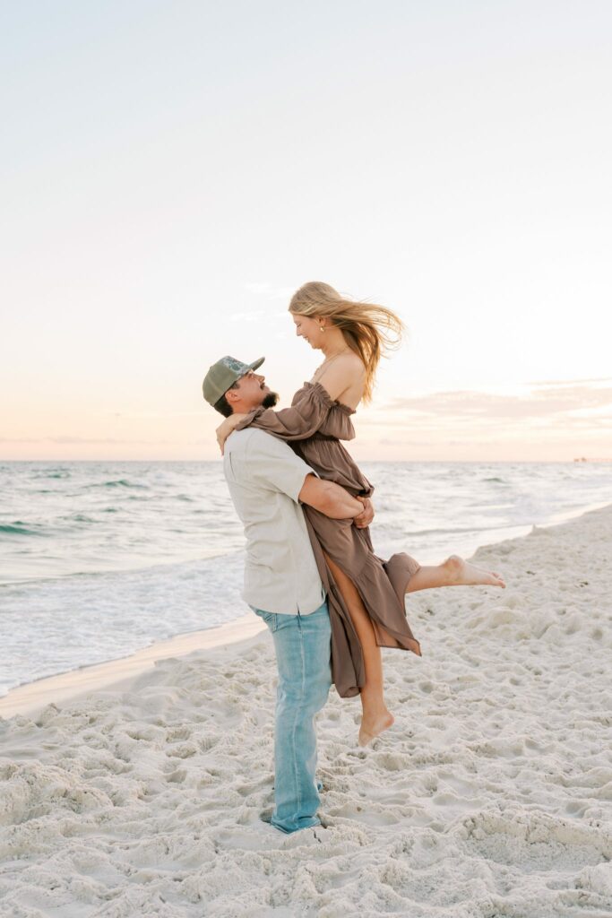 Avery & Hannah's Orange Beach Proposal 8 Avery lifts Hannah off the sand with the Gulf of Mexico behind them in their Orange Beach engagement photos