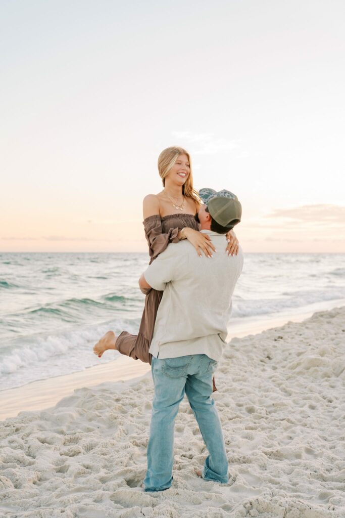 Avery & Hannah's Orange Beach Proposal 9 Hannah smiles down at Avery as he holds her up on the shoreline during their Orange Beach engagement session
