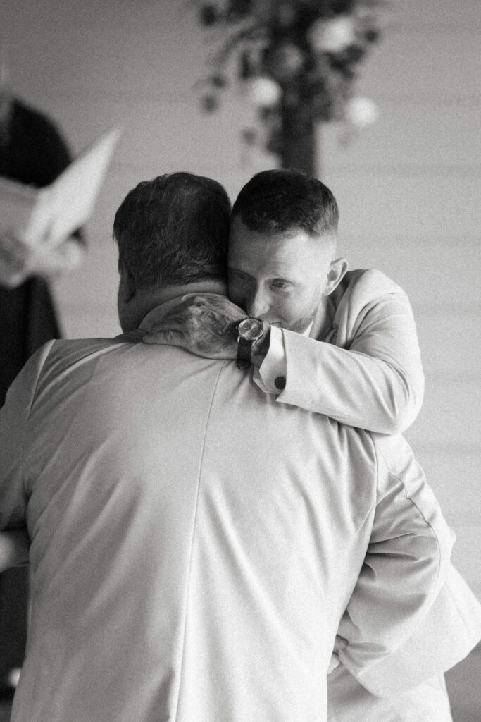Anthony & Renee's Wedding at The Venue at Hidden Falls 4 Black and white photo of Anthony in a long hug at his wedding ceremony at The Venue at Hidden Falls