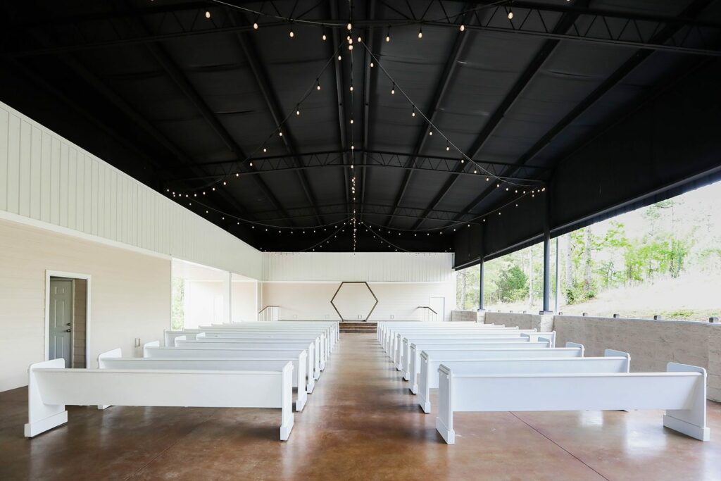 Anthony & Renee's Wedding at The Venue at Hidden Falls 6 Inside The Chapel at The Venue at Hidden Falls with white pews, string lights and open sides
