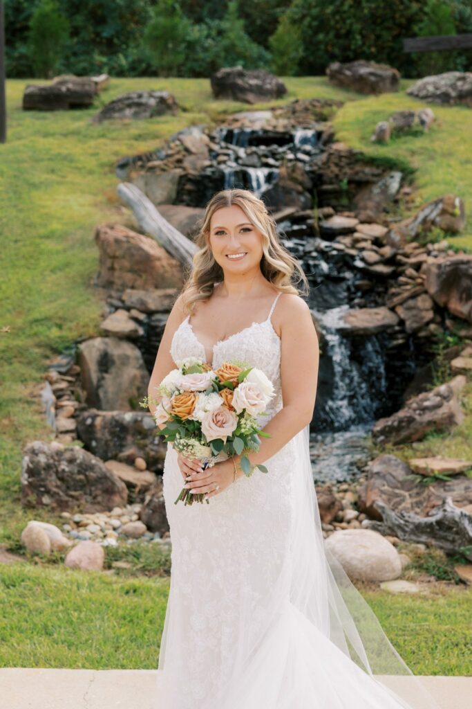 Anthony & Renee's Wedding at The Venue at Hidden Falls 7 Renee holding her bouquet in front of the waterfall at The Venue at Hidden Falls in Flomaton, Alabama