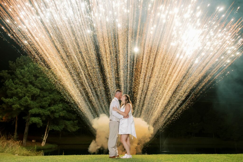Anthony & Renee's Wedding at The Venue at Hidden Falls 12 Anthony and Renee kissing in front of a burst of sparks by the pond at The Venue at Hidden Falls at night