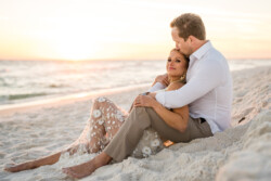 Pensacola Engagement Photography: A Dreamy Fort Pickens Session with Ryan & Kinsie 15 a man and woman sitting on a beach embracing each other during their engagement photo sessions at at Fort Pickens by KDH Weddings