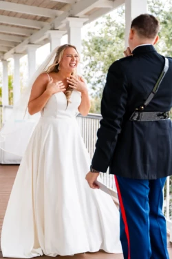 A Perfect USMC Wedding in Pensacola – Bobby & Kaisey’s Big Day 21 groom in dress blues first look at bride in white dress smiling