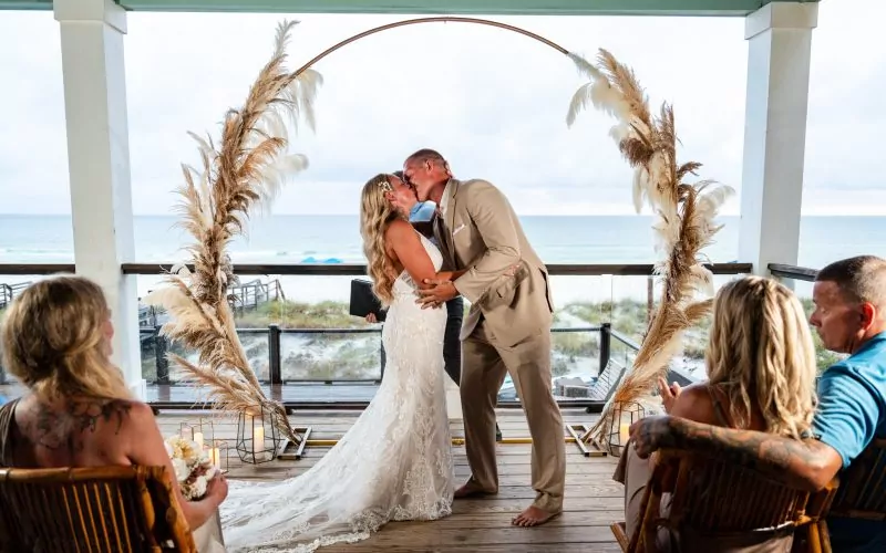 a man and woman kissing under an arch first kiss after getting married in destin fl | KDH Weddings