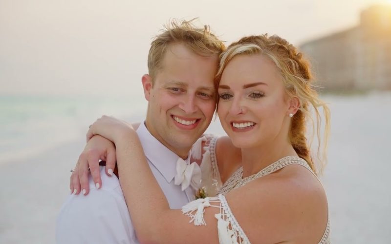 Kevin and Josie holding each other on the beach in warm sunset light, a still from their destination wedding film