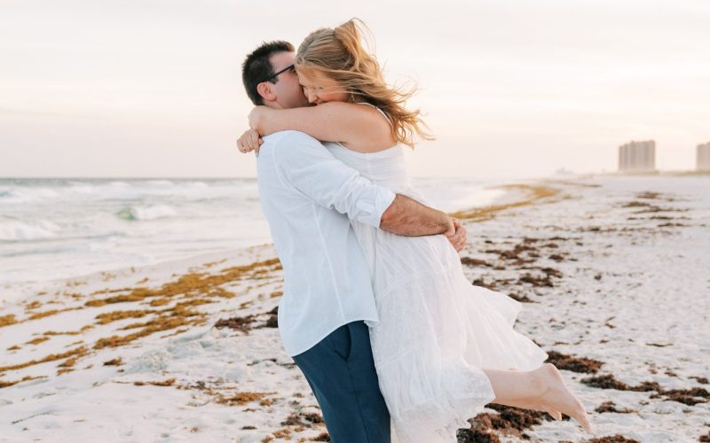 Andrew lifts Katie into a hug at the water's edge during their Pensacola Beach engagement session