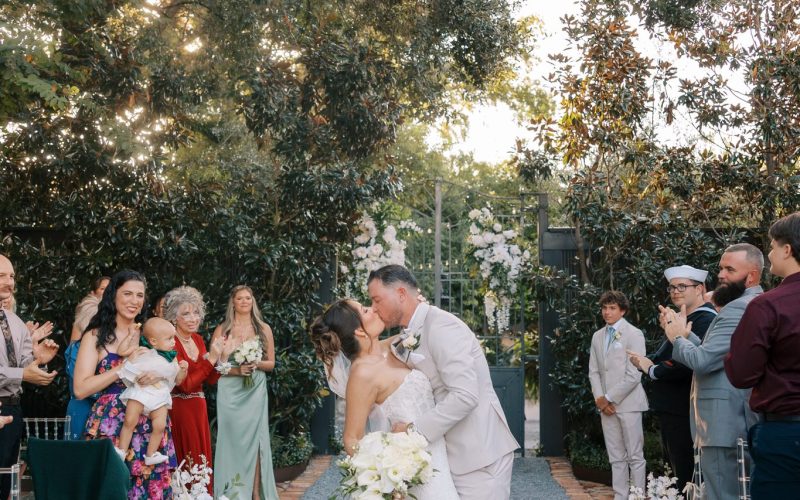 Nick and Amanda kiss at the end of the garden ceremony aisle at Supposey Warehouse and Gardens in Pensacola